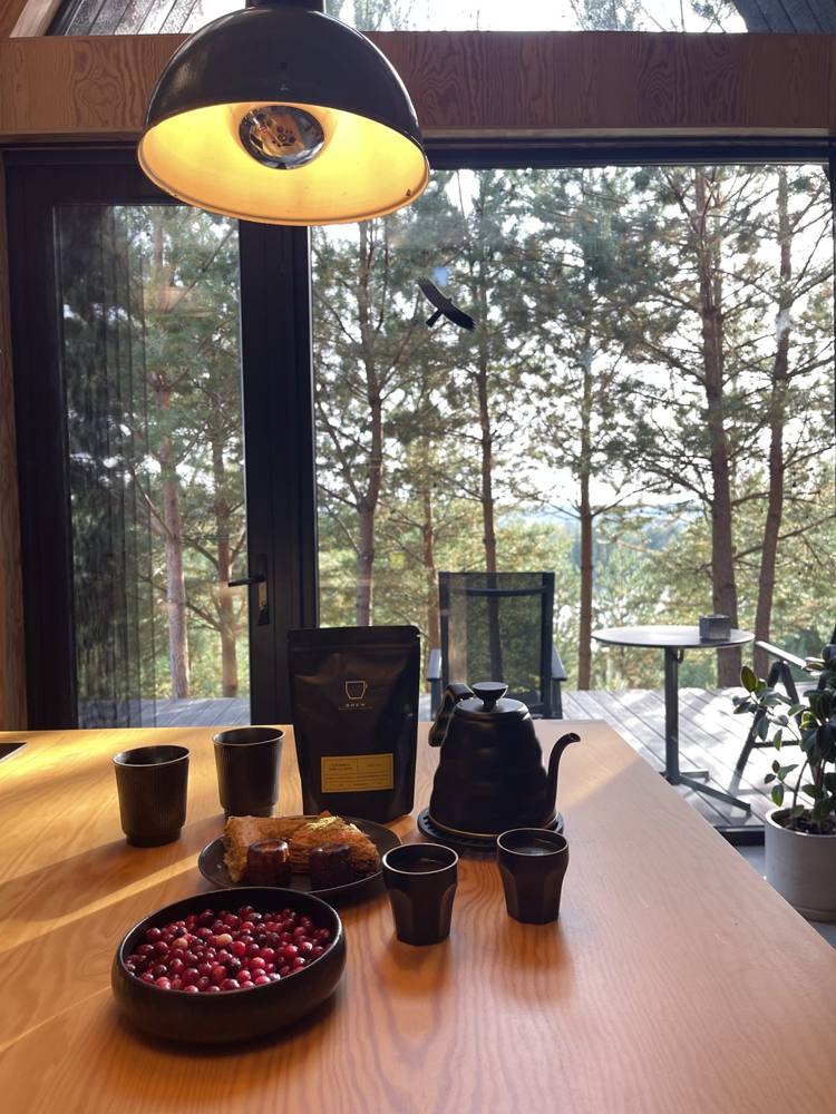 Coffee on a wooden table with a view of pine trees and the lake