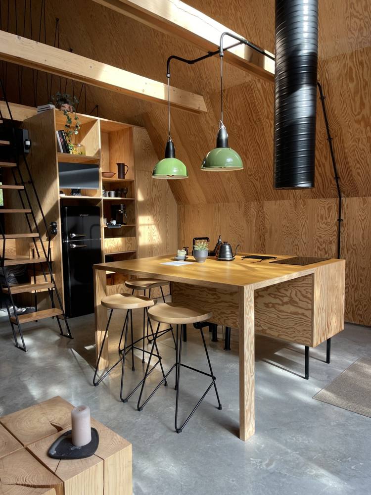 Wooden kitchenette and dining table inside an A-frame cabin in Lithuania