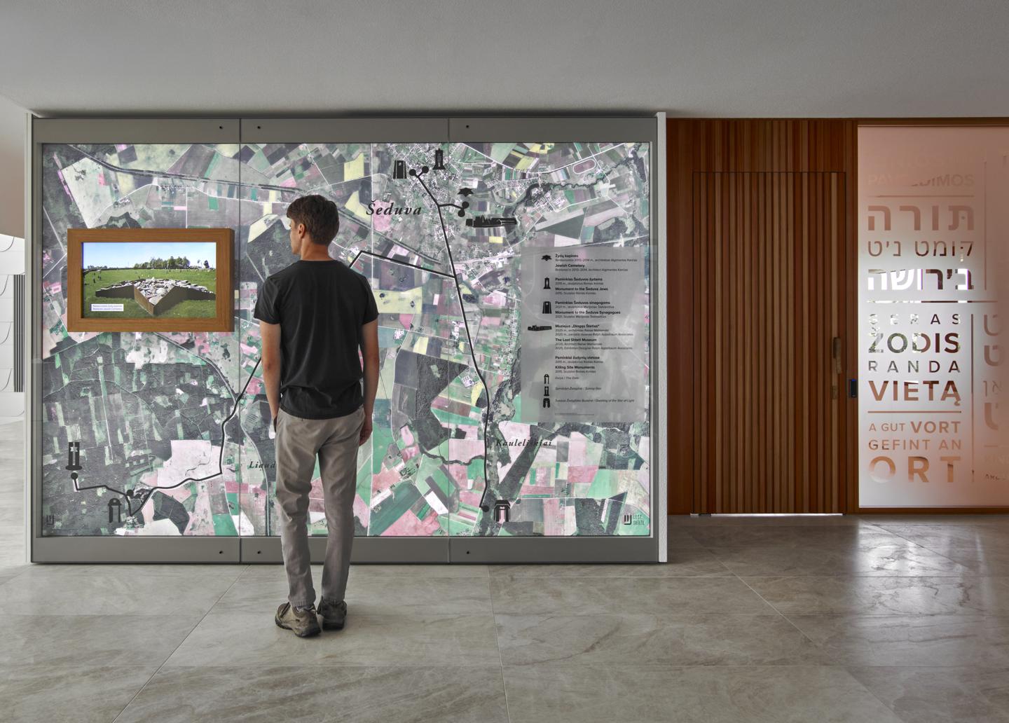 A visitor studies a large aerial map of Šeduva and its memorial sites