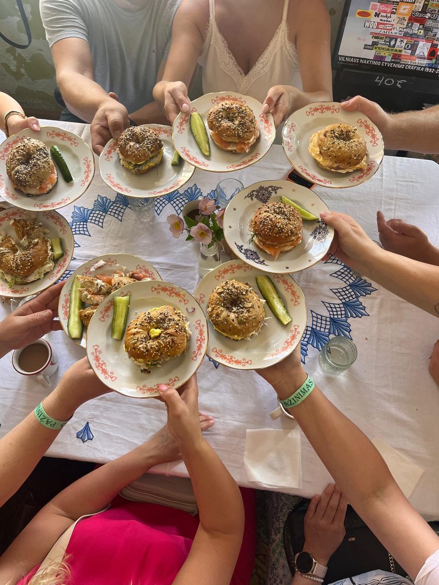 Guests passing plates of seeded sourdough bagels around a table
